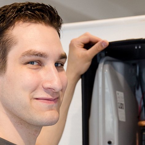 Mit einem zufriedenen Ausdruck überprüft der junge Techniker die Innenteile eines Geräts, das für die Heiztechnik verwendet wird.