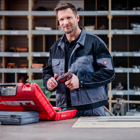 Ein Mann in Arbeitskleidung steht an einer Werkbank