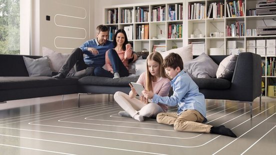 Eine Familie die in einem Wohnzimmer ist, in dem die Kinder auf dem Boden sitzen